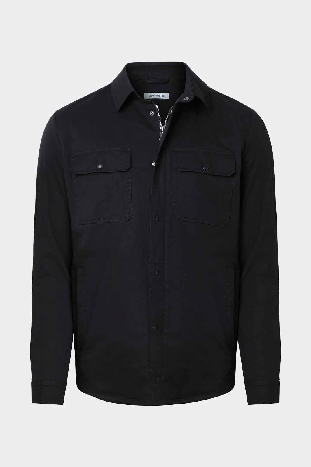 Vue sur fond blanc d'une surchemise en 100% coton noir avec fermeture zippée et pression boutonnée et poches à rabat boutonnés.