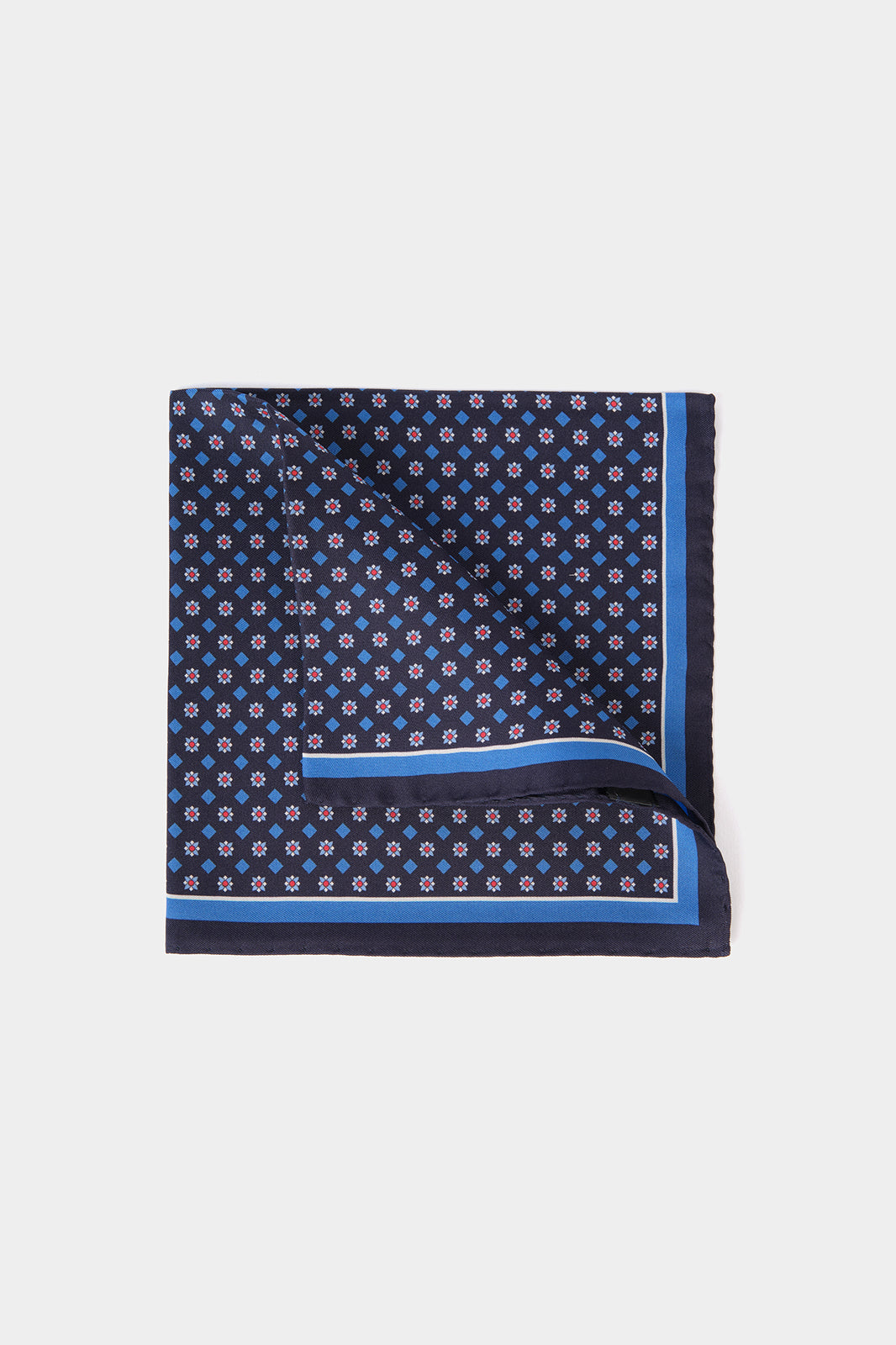 Vue sur fond blanc d'une pochette en 100% soie fond bleu marine à motifs géométriques
