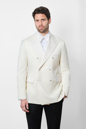 Vue sur fond blanc d'un smoking ou tuxedo veste blanche et pantalon noir à patte de serrage et noeud papillon en soie