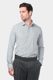 Un homme vêtu d'une chemise à rayures kaki et blanches avec un col français. Il porte également un pantalon gris foncé à pinces.