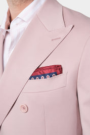 Vue rapprochée des revers pointues du costume rose poudré et de la pochette de costume rouge et bleue présent dans la poche de la veste.