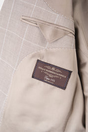 Zoom sur l’étiquette et la poche intérieure de la veste du costume beige à carreaux.