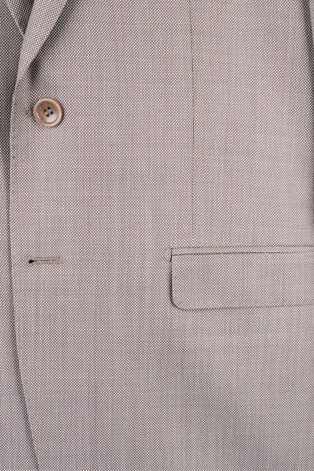 Gros plan sur la veste à deux boutons avec des poches à rabat en tissu grain de caviar beige.