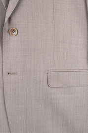 Gros plan sur la veste à deux boutons avec des poches à rabat en tissu grain de caviar beige.