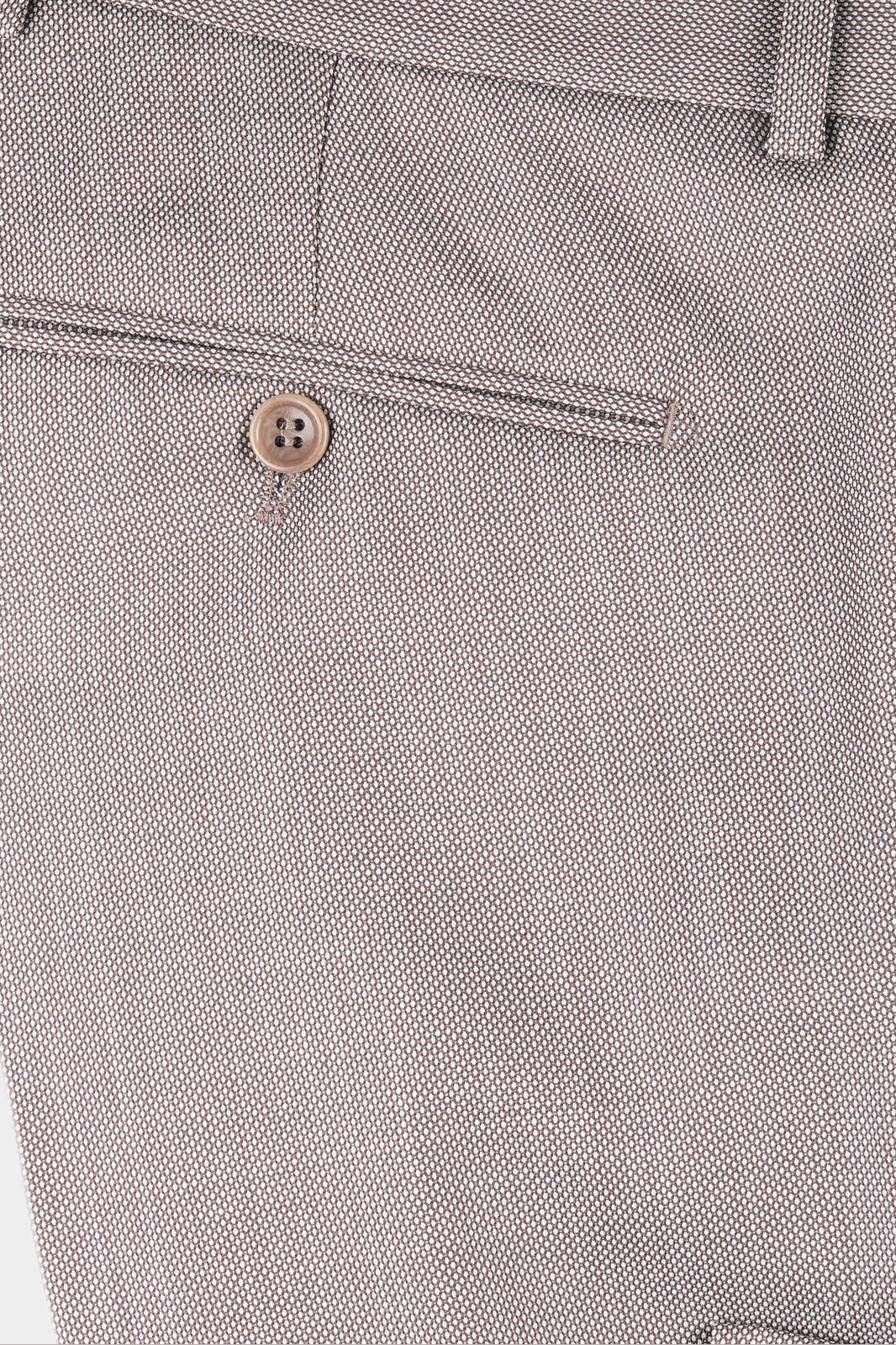 Plan rapproché sur le pantalon de costume en tissu grain de caviar beige.