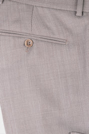 Plan rapproché sur le pantalon de costume en tissu grain de caviar beige.