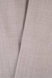 Plan rapproché sur le pantalon de costume en tissu grain de caviar beige.