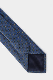 Cravate enroulée bleu avec un imprimé vert kaki, vue arrière et à plat.