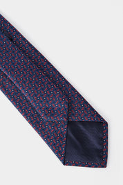 Cravate enroulée bleu marine avec un imprimé rouge vue arrière et à plat.