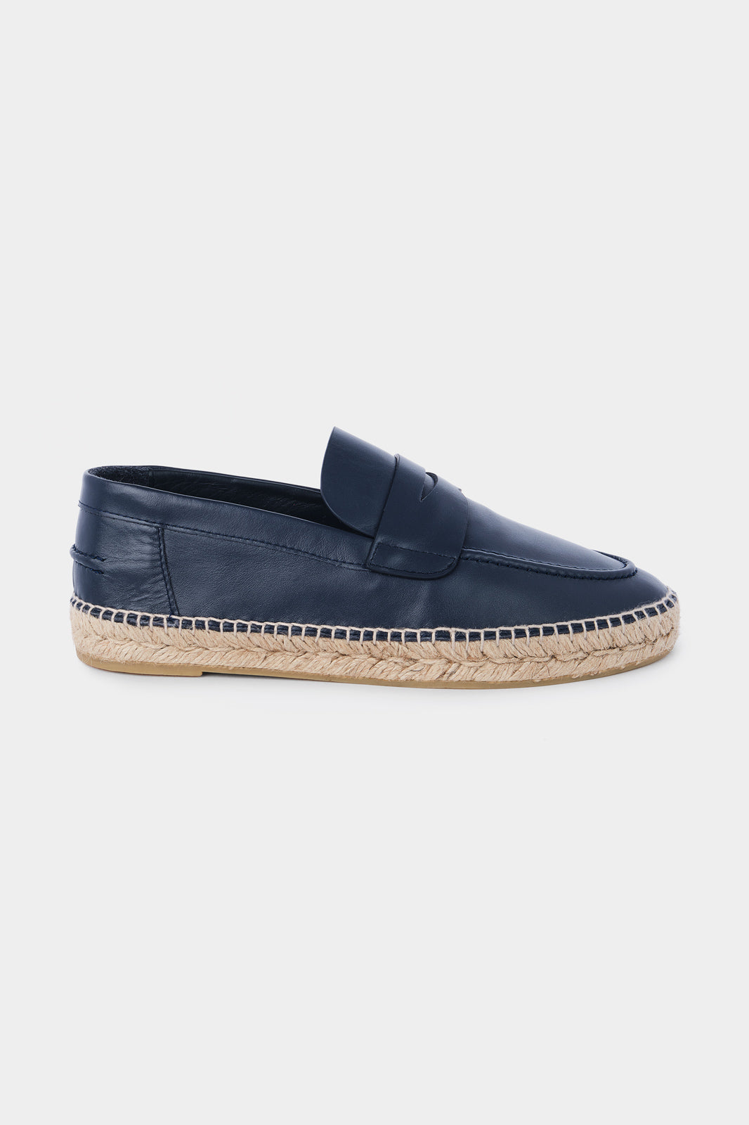 Vue de côté d'une espadrille en cuir bleu marine avec une semelle en corde tressée. Elle a un design de mocassin avec des coutures apparentes sur le dessus.