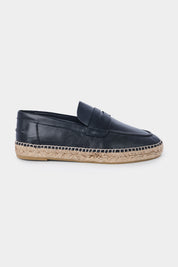 Vue de côté d'une espadrille en cuir noir avec une semelle en corde tressée. Elle a un design de mocassin avec des coutures apparentes sur le dessus.