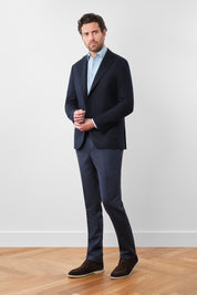Vue sur mannequin portée d'un blazer marine uni avec une trame bayadére ton sur ton sur un tissu de chez E.Thomas. Vous apprécierez sa coupe cintrée, son montage napolitain (non-doublée et non-épaulée) avec les poches plaquées sur le devant.