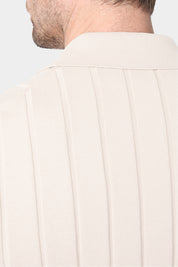 Un gros plan de dos d'une chemise polo beige avec des rayures verticales, mettant en évidence le col. Le tissu présente une matière en maille fine en coton.