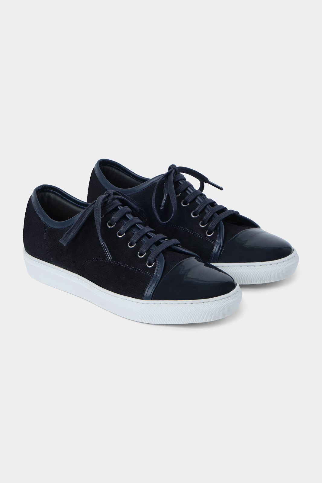 Vue sur fond blanc de la sneaker marine bout verni en peau et cuir vernir à lacet avec une semelle blanche épaisse.