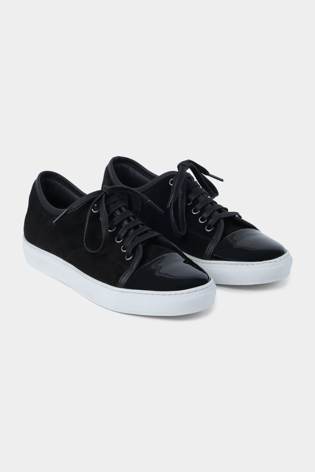 Vue sur fond blanc de la sneaker noir bout verni en peau et cuir vernir à lacet avec une semelle blanche épaisse.