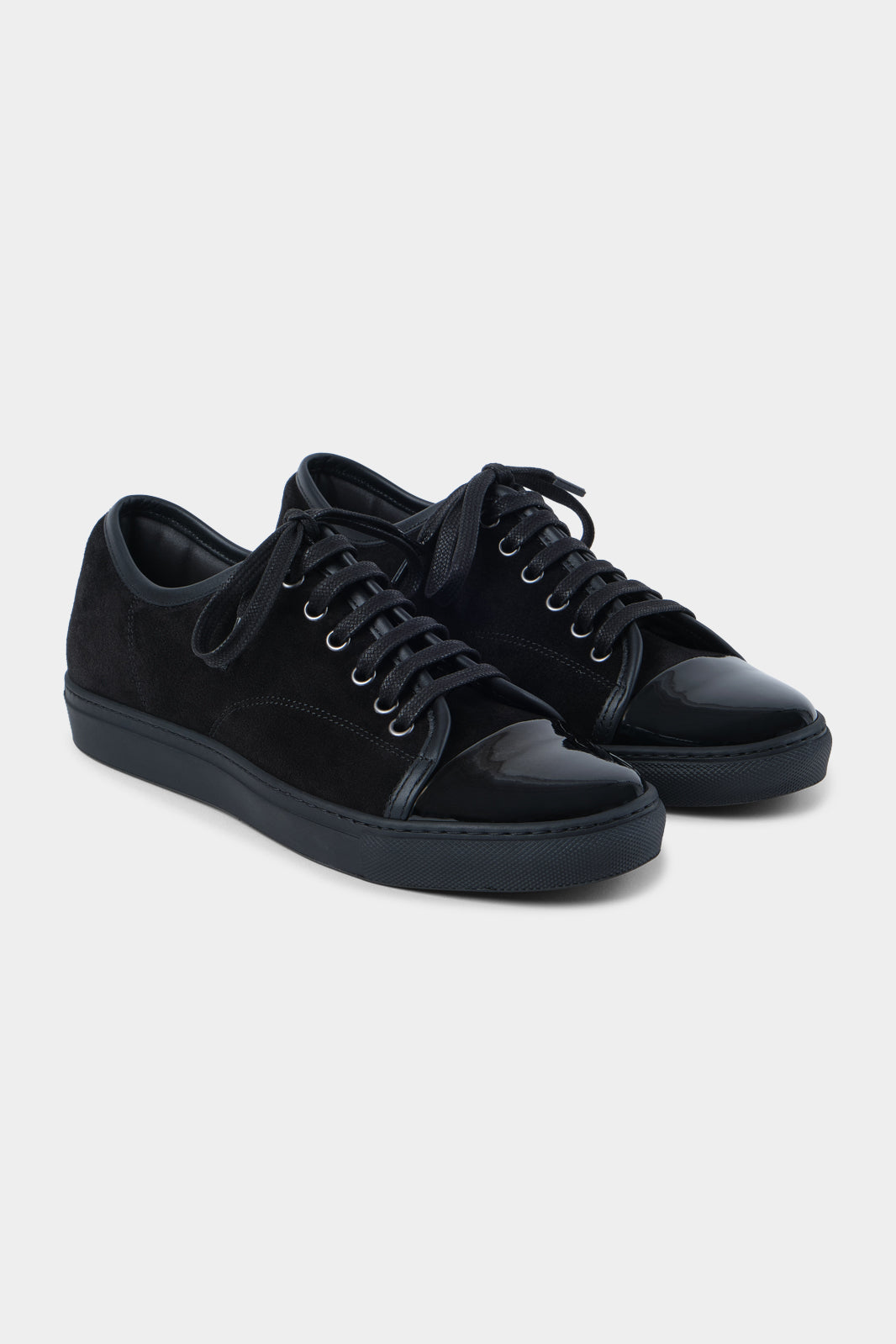 Vue sur fond blanc de la sneaker noir bout verni en peau et cuir vernir à lacet avec une semelle noire épaisse.