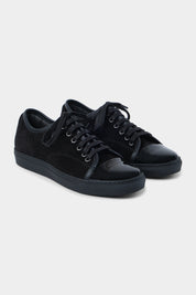 Vue sur fond blanc de la sneaker noir bout verni en peau et cuir vernir à lacet avec une semelle noire épaisse.