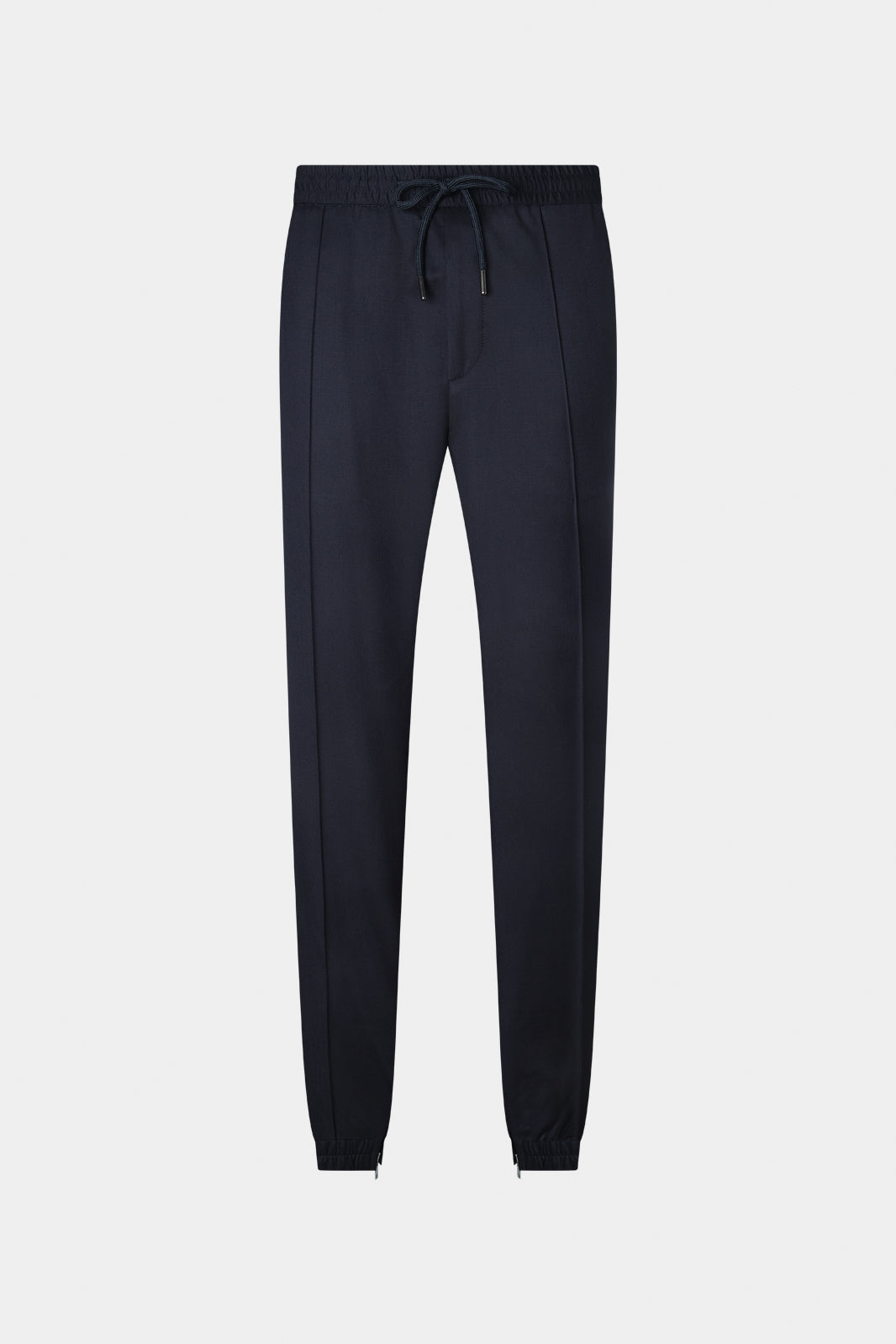 Vue sur un fond blanc d'un pantalon marine avec une taille élastiquée et un cordon. Il y a un zip en bas de jambe et il est resserré à la chevil.