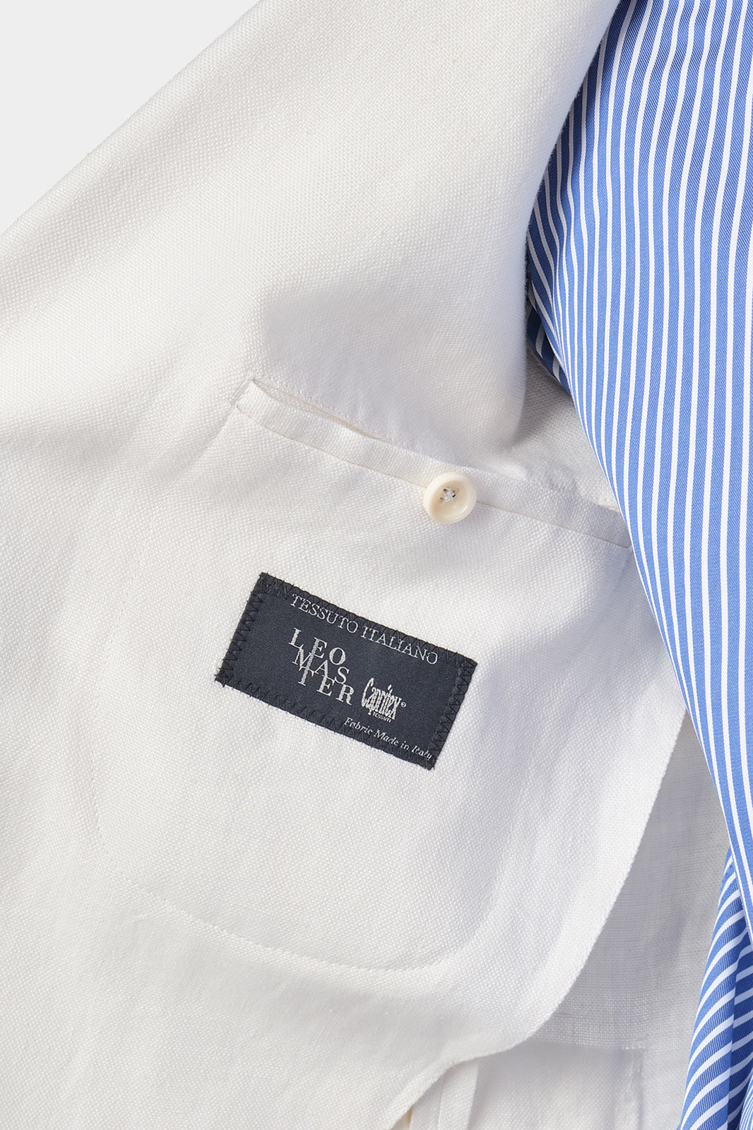 Zoom sur l’étiquette et la poche intérieur du costume en lin blanc que l’homme porte.