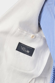 Zoom sur l’étiquette et la poche intérieur du costume en lin blanc que l’homme porte.