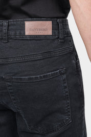 Zoom sur un homme de dos portant un jean en coton et élasthanne de couleur noire. Il porte également un tee-shirt en coton glacé noir.