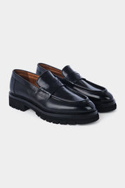 Photo de mocassins en cuir patiné noir, dotés d'une semelle crantée antidérapante en gomme pour un confort absolu et une adhérence optimale.