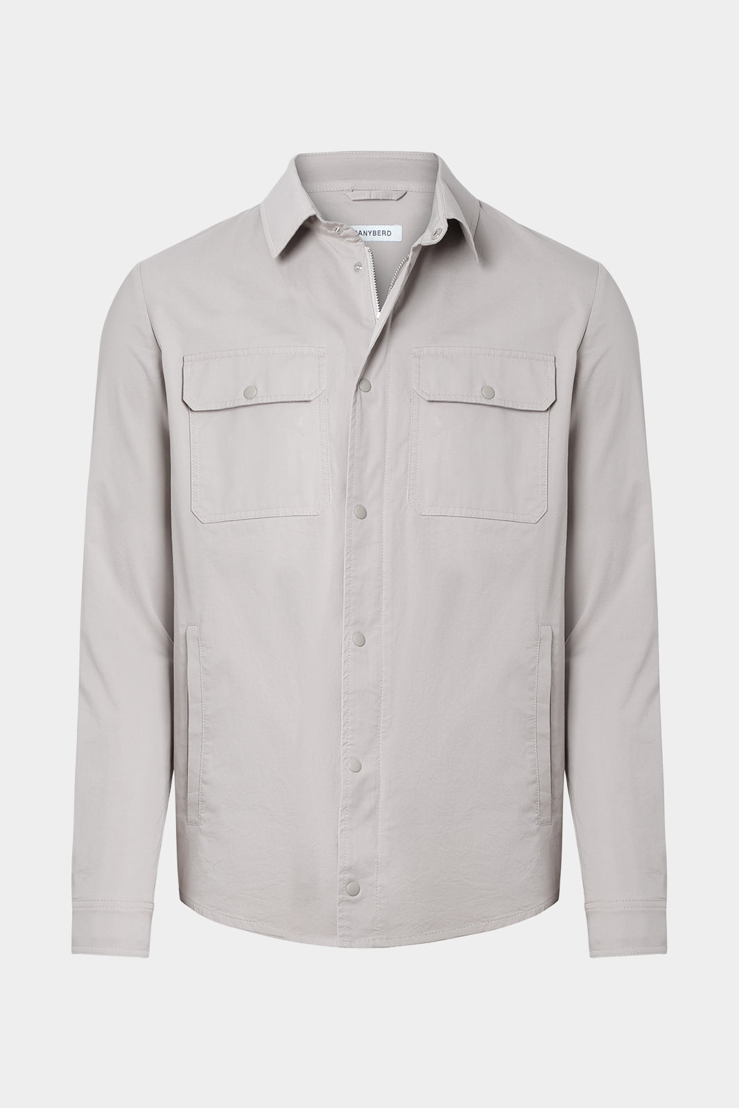 Vue sur fond blanc d'une surchemise en 100% coton beige avec fermeture zippée et pression boutonnée et poches à rabat boutonnés.
