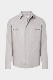 Vue sur fond blanc d'une surchemise en 100% coton beige avec fermeture zippée et pression boutonnée et poches à rabat boutonnés.