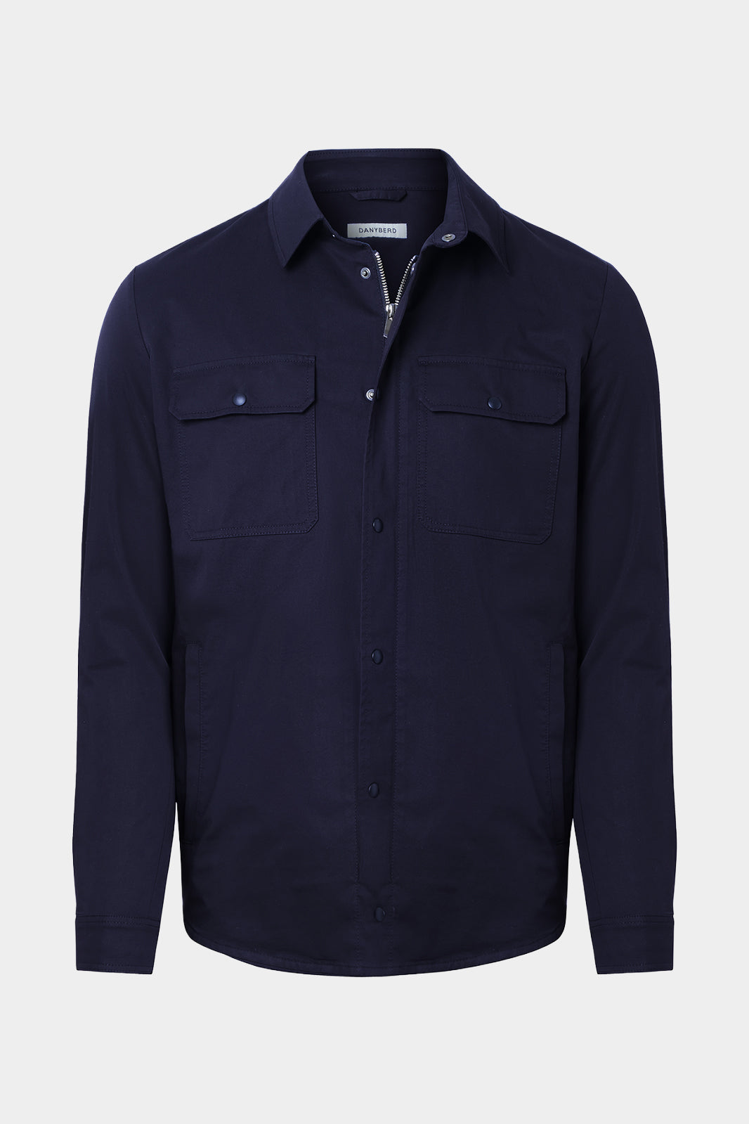 Vue sur fond blanc d'une surchemise en 100% coton marine avec fermeture zippée et pression boutonnée et poches à rabat boutonnés.