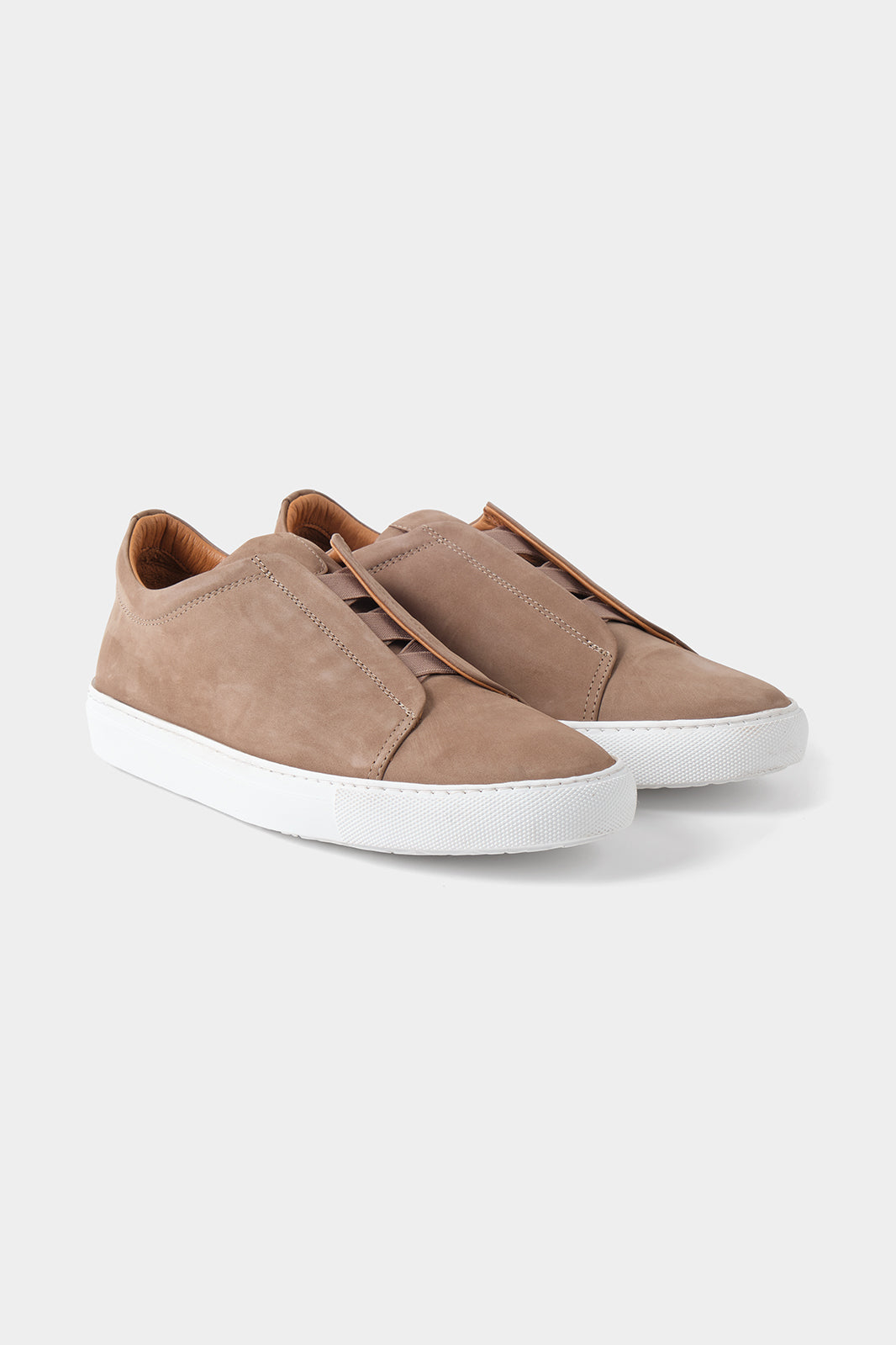 Vue sur fond blanc d'une sneaker en peau beige sans lacet avec une semelle blanche épaisse.