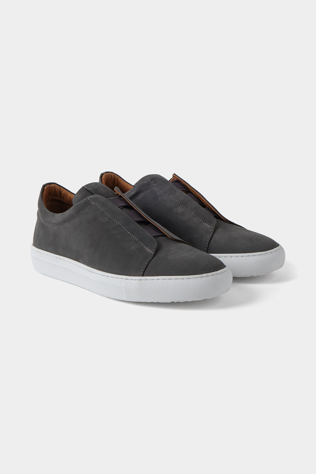 Vue sur fond blanc d'une sneaker en peau grise sans lacet avec une semelle blanche épaisse.