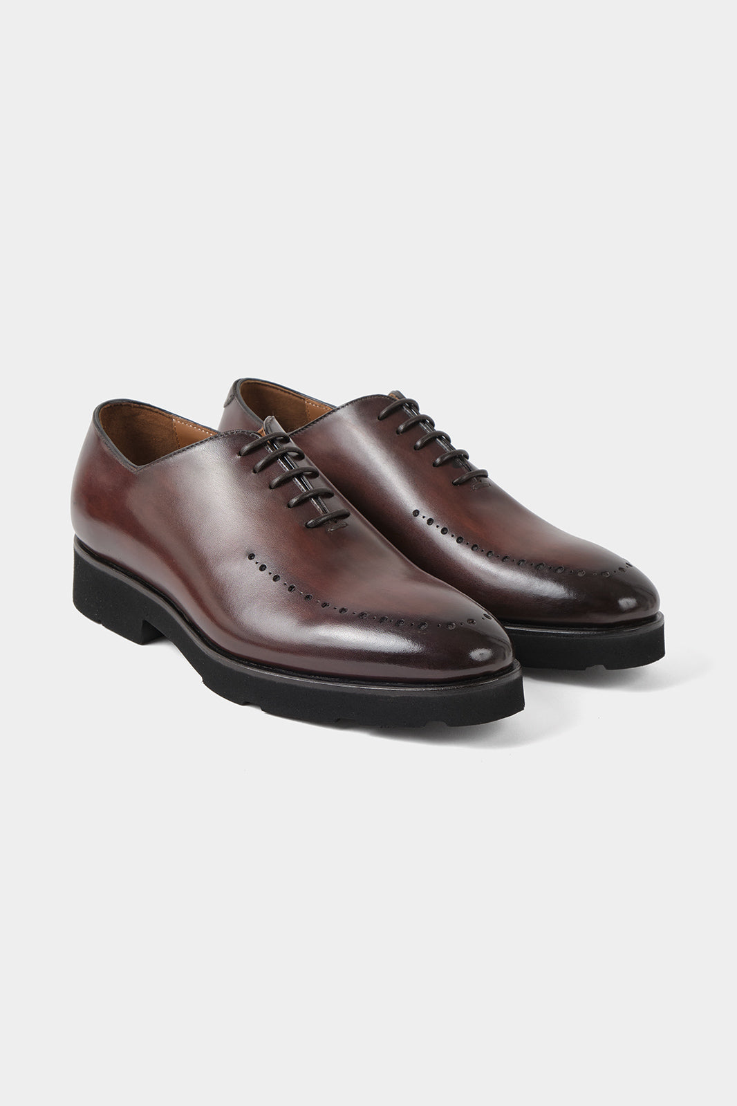Vue sur fond blanc d'une paire de souliers à lacets patiné avec œillets marron en cuir