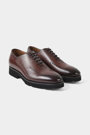 Vue sur fond blanc d'une paire de souliers à lacets patiné avec œillets marron en cuir