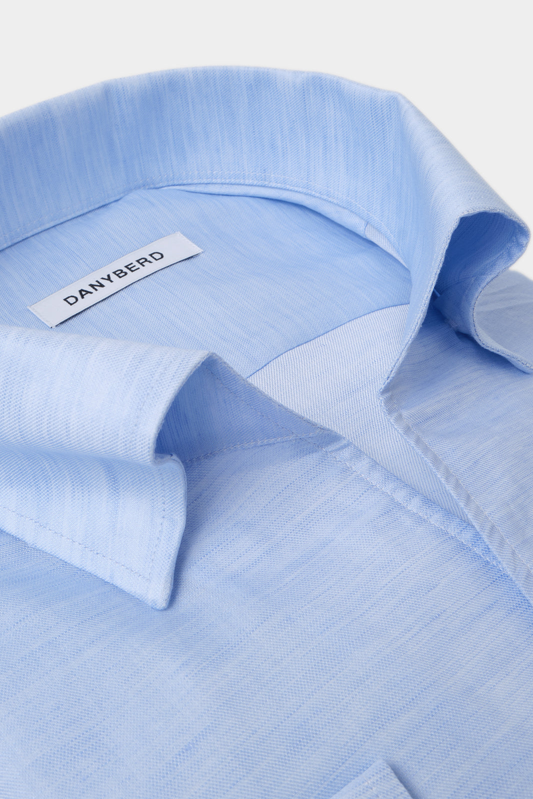 Vue sur fond blanc d'une chemise col indien avec boutonnage sous patte appelé aussi col capri en bleu ciel en coton et lin.
