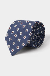Vue sur fond blanc d'une cravate en tissu mélangé en Bleu à motifs fleurs blanches et marrons 