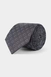 Vue sur fond blanc d'une cravate en 100% soie de couleur grise à motif rond.