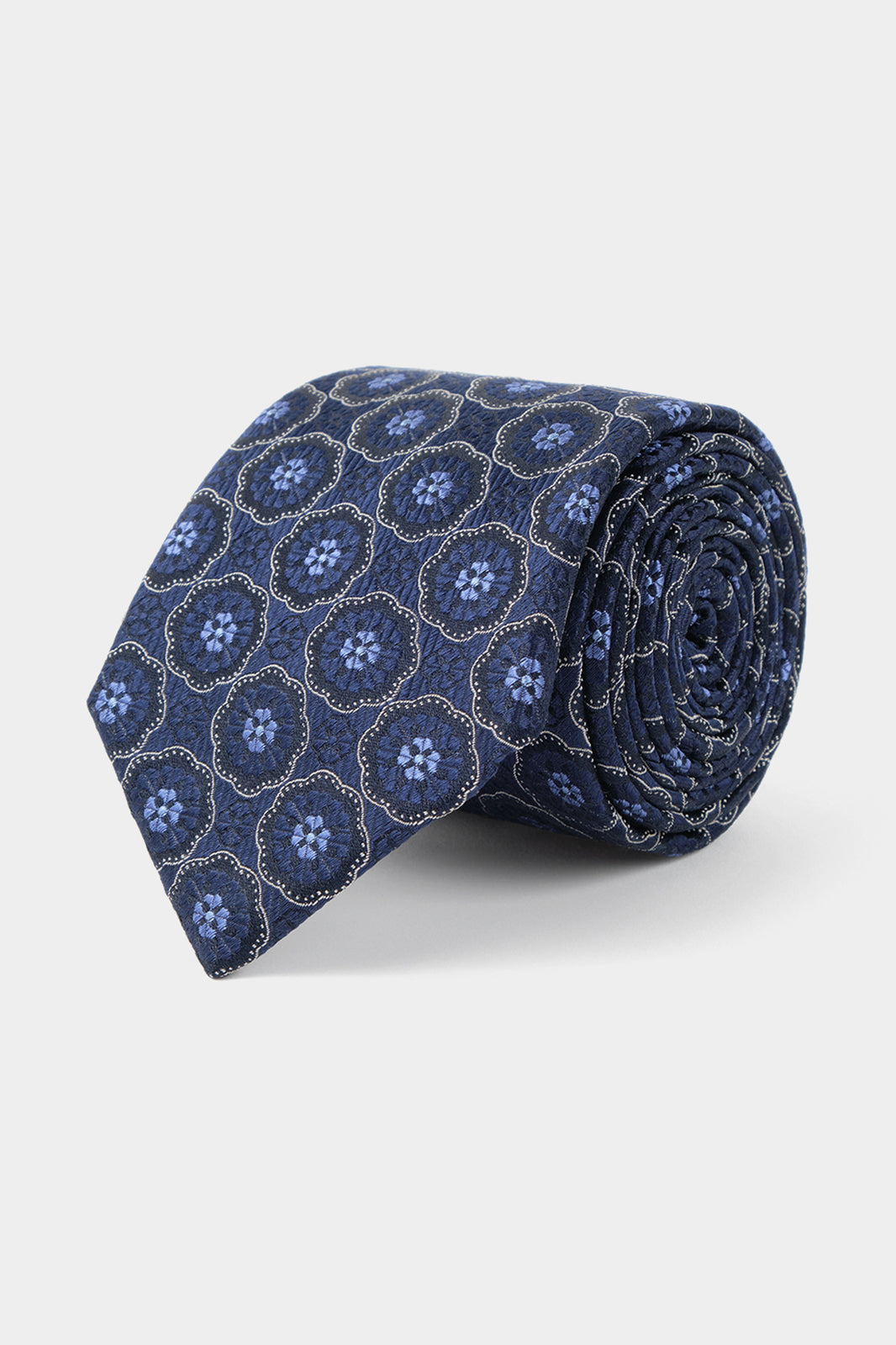 Vue sur fond blanc d'une cravate en 100% soie en bleu à motifs fleurs