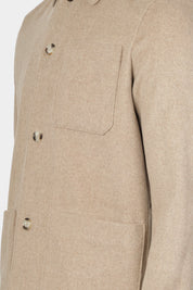 Vue sur fond blanc du blouson worker couleur beige, avec 2 poches plaqués ainsi qu'une poche poitrine.