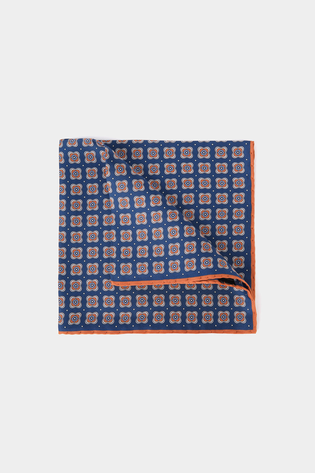 Vue sur fond blanc d'une pochette en 100% soie fond bleu marine à motifs floral géométrique orange et blanc
