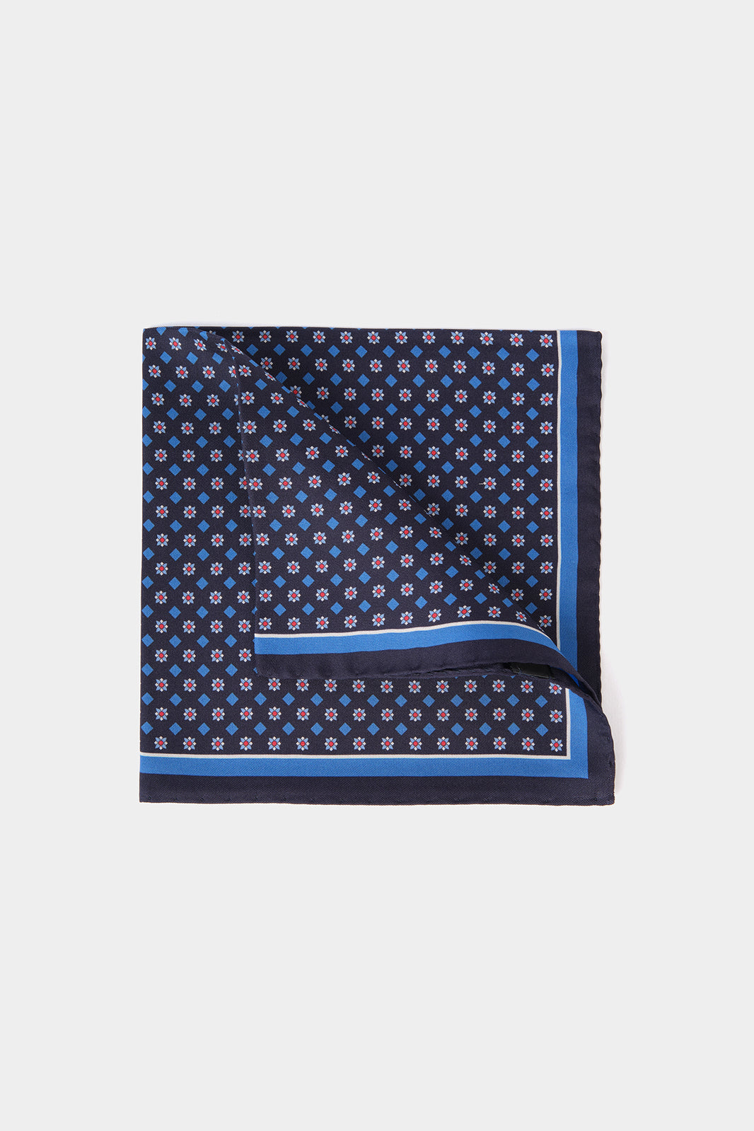 Vue sur fond blanc d'une pochette en 100% soie fond bleu marine à motifs géométriques 