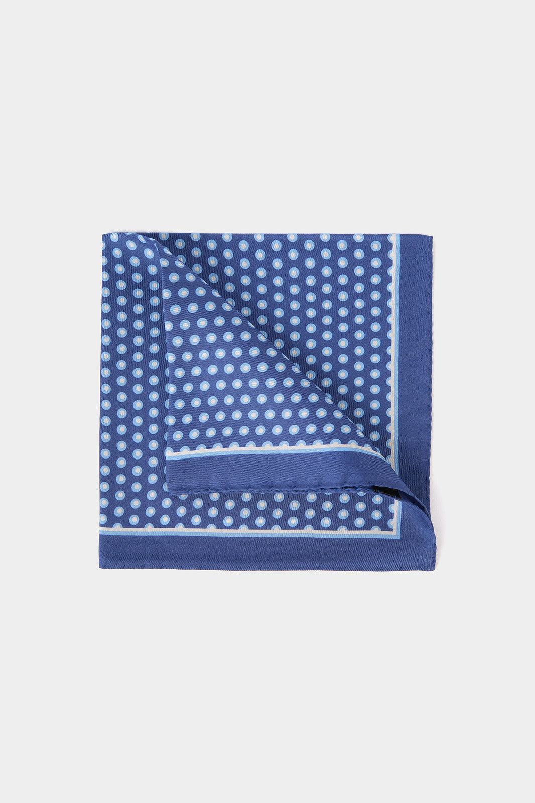 Vue sur fond blanc d'une pochette en 100% soie sur un fond bleu lumineux à motif pois blanc et bleu clair