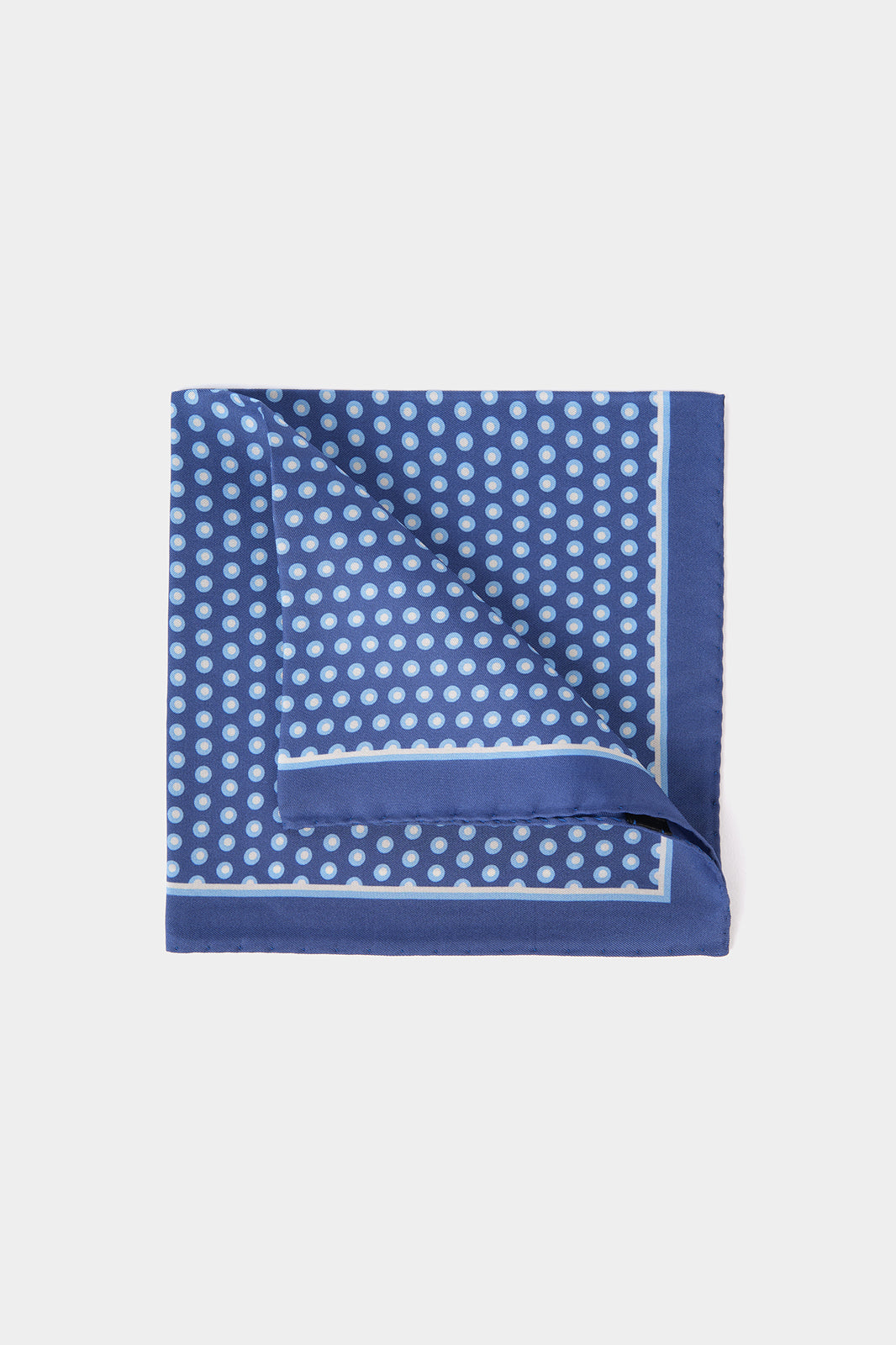 Vue sur fond blanc d'une pochette en 100% soie sur un fond bleu lumineux à motif pois blanc et bleu clair