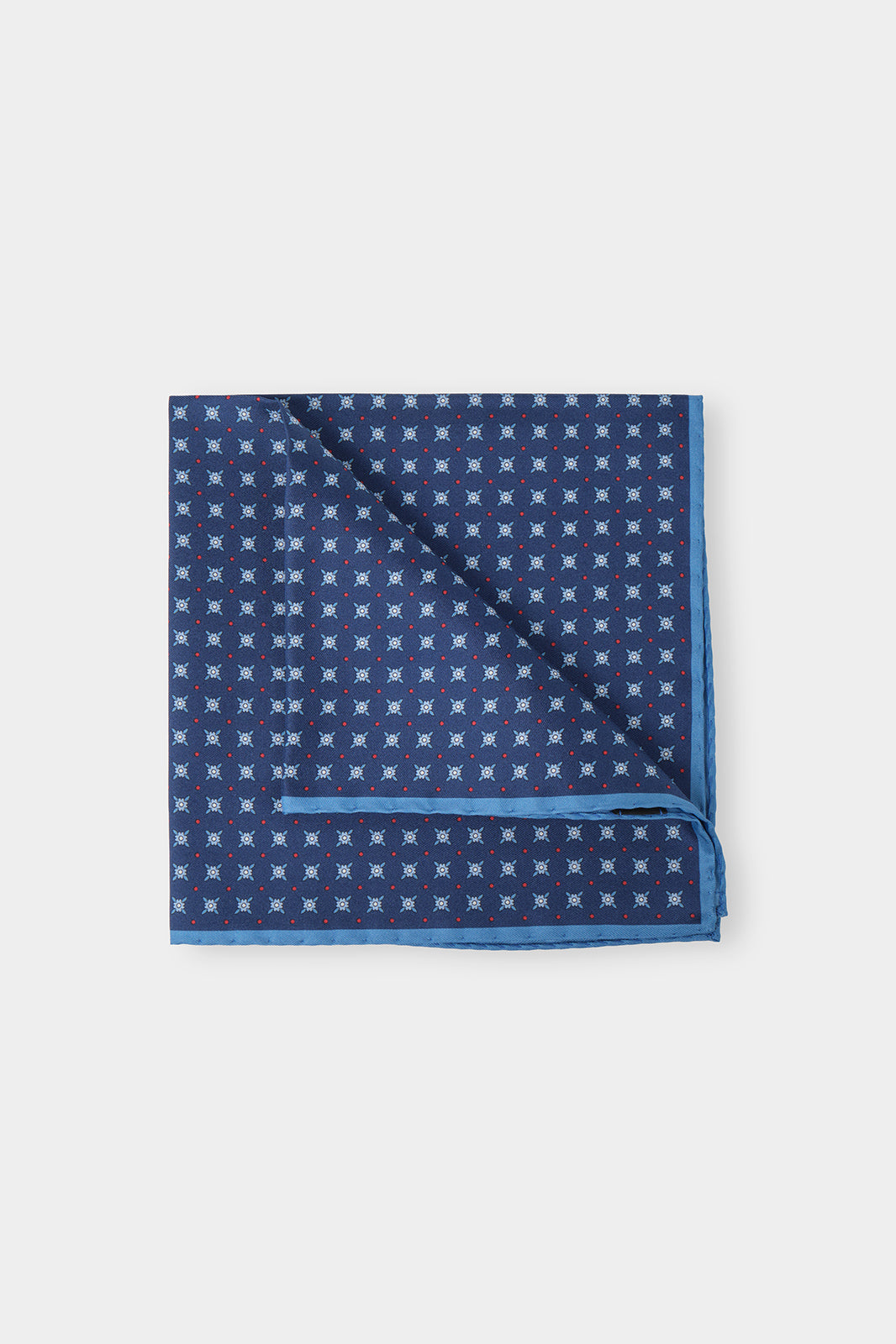Vue sur fond d'une pochette marine à fleurs marine en 100% soie fabriqué en Italie.