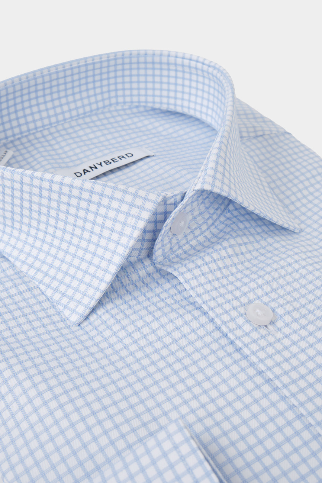 Vue sur fond blanc d'une chemise col français non cintrée - Blanche à carreaux bleus. Sur un tissu italien en 100% coton.