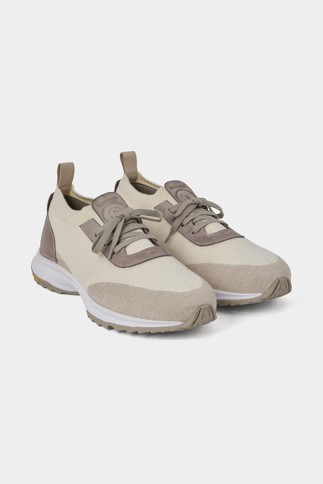 Vue sur fond blanc d'une paire de sneakers beige avec extérieur en textile, intérieur en cuir et semelle épaisse blanche de chez Vibram avec lacets beige.