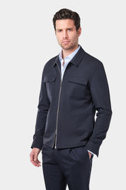 Un homme vêtu d'un blouson bleu marine en tissu Olmetex imperméable et coupe-vent décontracté avec 4 poches, une fermeture à double zip et un col. Il porte également une chemise en coton à fines rayures bleues avec un col français et un pantalon bleu marine à pinces.