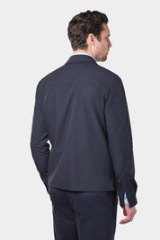  Un homme de dos vêtu d'un blouson bleu marine en tissu Olmetex imperméable et coupe-vent décontracté avec 4 poches, une fermeture à double zip et un col. Il porte également une chemise en coton à fines rayures bleues avec un col français et un pantalon bleu marine à pinces