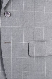 Zoom sur la matière et la poche plaquée de la veste du costume gris à carreaux. 
