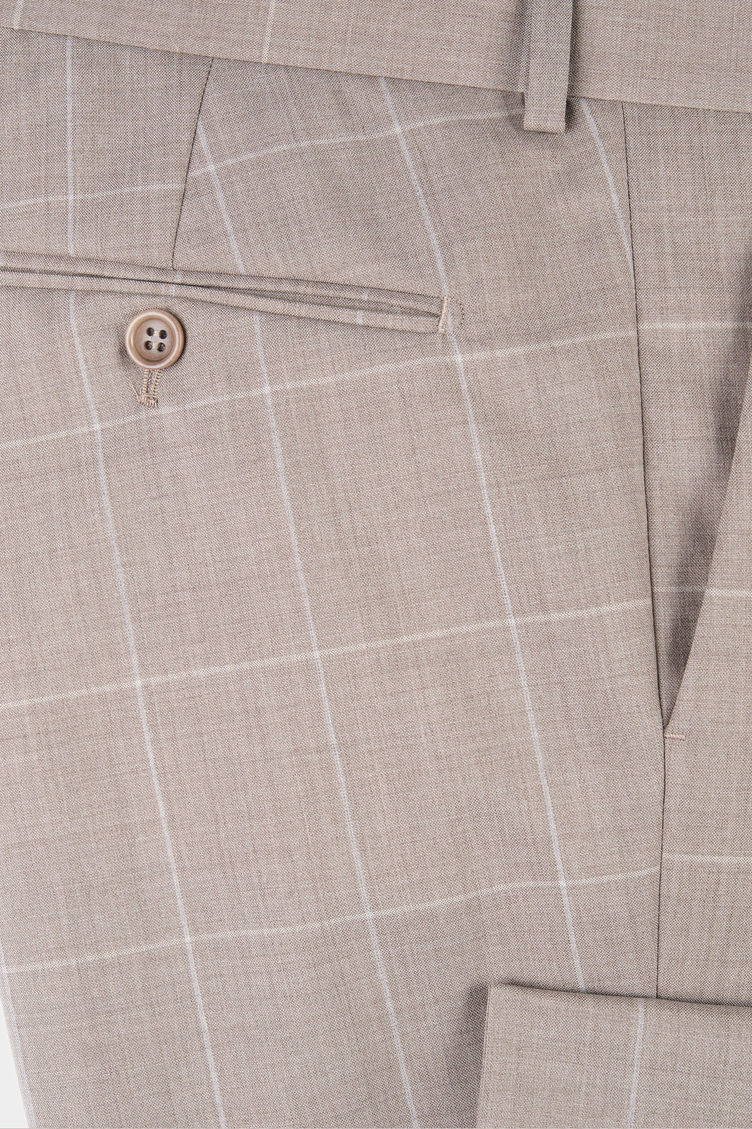 Zoom sur la matière et la poche arrière du pantalon de costume beige à carreaux. 