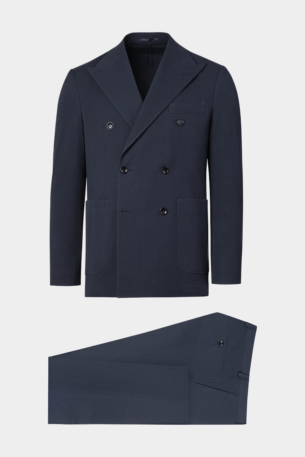 Vue sur fond blanc d'un costume Seersucker croisé couleur marine. Sur un tissu italien en 97% coton gaufré 3% élasthanne de chez Subalpino.